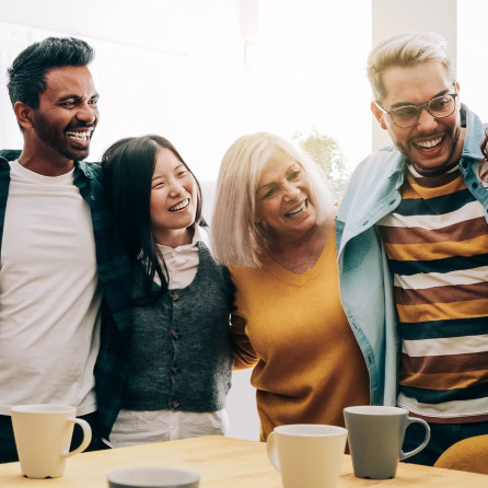 People standing together with arms around each other facing the camera looking at someone behind camera