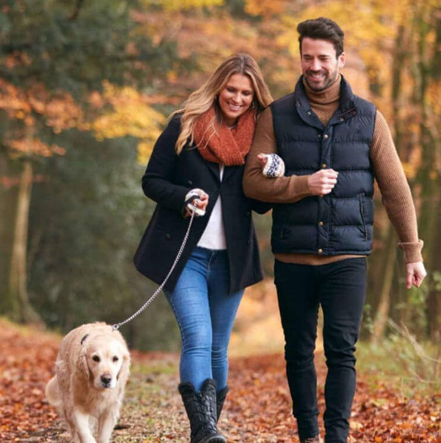 Woman and man walking dog in the woods